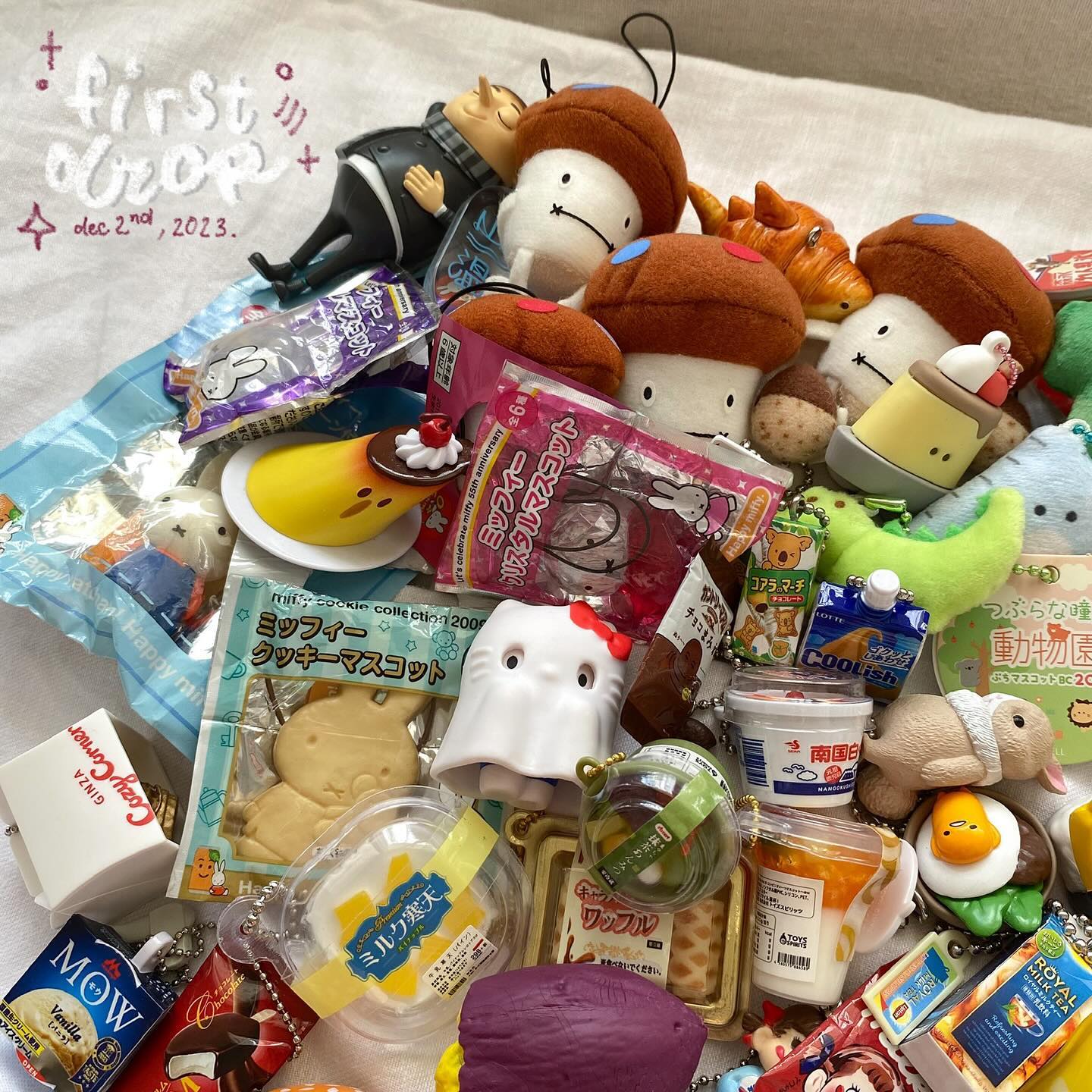 the image shows a collection of various items, including plush toys resembling mushrooms and other characters, figurines, japanese snacks and desserts in their packaging, keychains, and foodthemed items like a pudding figurine and a croissant plush toy. there are also packaged sweets, chocolate, and drinks visible. the items are piled together on a white surface. a "first crop" message with the date "dec 2nd, 2023" is visible in the upper left.