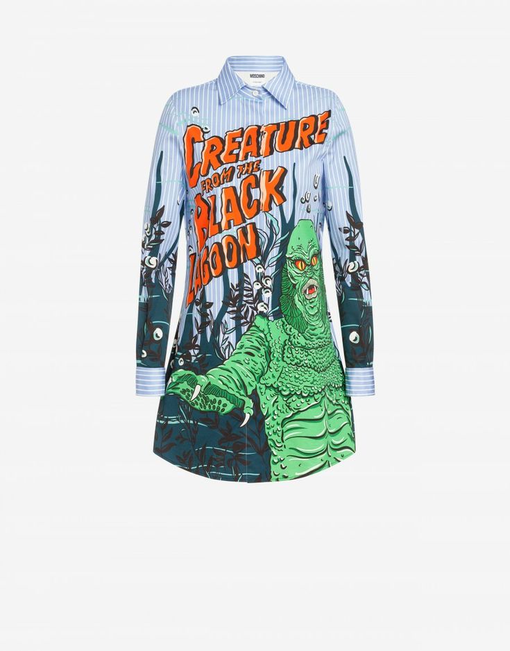 a "creature from the black lagoon" graphic print dress with long sleeves is displayed on a white background. the dress has a collared neckline and vertical blue and white stripes on the upper portion, while the graphic print of the iconic monster is featured on the lower part.