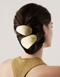 a woman with long, dark brown hair is wearing a gold hair clip in her hair. she is looking away from the camera, and her face is partially obscured by her hair. the woman is wearing a brown sweater, and she has a beautiful, natural look.