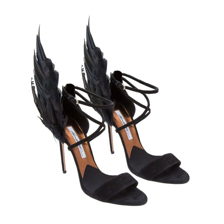 a pair of black highheeled sandals with black feather embellishments on the back of the ankle straps, set against a white background. the shoes have a stiletto heel and a strap across the toes, with an additional ankle strap.