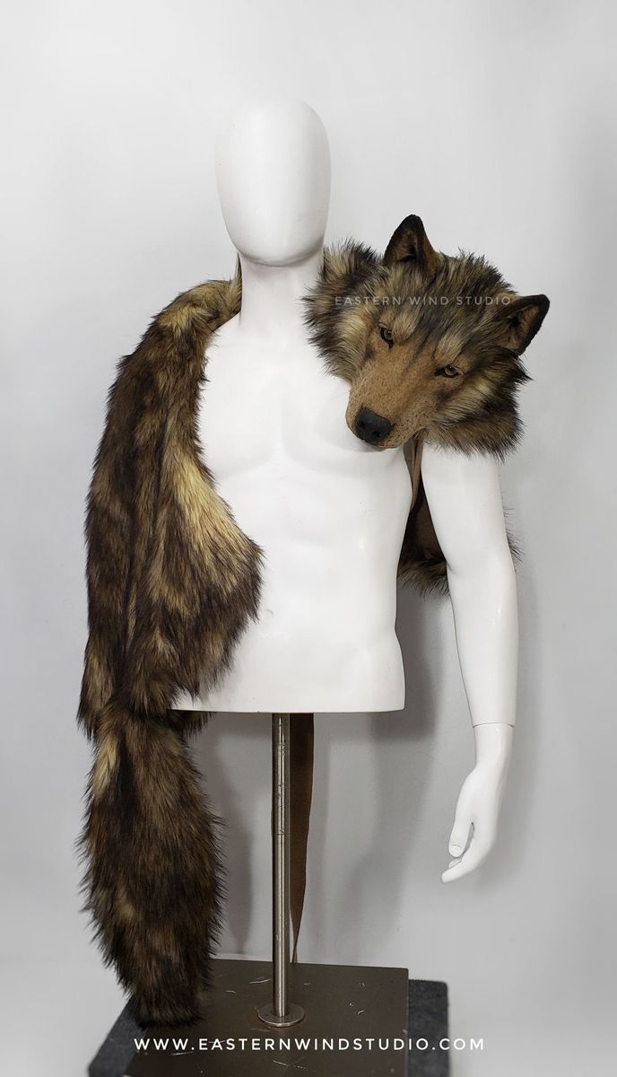 a studio shot of a fur wolf shoulder piece draped on a white mannequin. the shoulder piece has a realistic wolf head on one shoulder, and a long fur tail hanging down the other side. the mannequin is standing on a metal stand. the website "www.easternwindstudio.com" is visible at the bottom of the image.