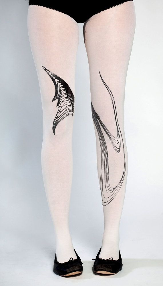 a full shot of a person from the knees up wearing white tights with black patterns, and black ballet flats. the left leg has a dense, layered, winglike design around the knee, while the right leg features a flowing, multiline design that extends down the shin. the person is standing on a white background. the person is wearing black bottoms.