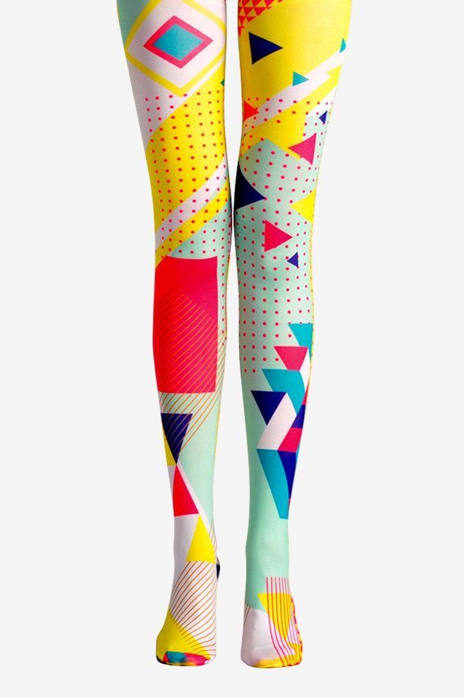 the image shows a pair of tights or leggings with a vibrant and colorful geometric pattern. the pattern includes various shapes like triangles, diamonds, and polka dots in bright colors. the tights are being worn on a pair of legs. the overall style is bold and fashionable.