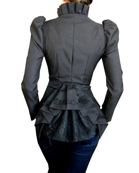 a woman is pictured from the back wearing a gray jacket with a ruffled collar and a layered, ruffled hemline that extends down to her upper thighs. underneath the jacket, she is wearing blue denim jeans. the jacket has long sleeves. the style of the jacket appears to be unique and fashionforward.
