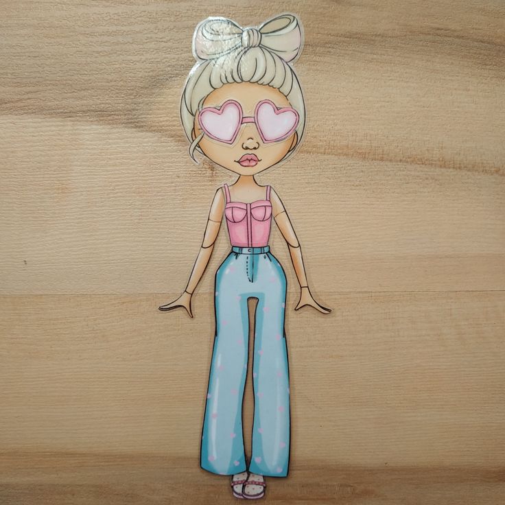 a drawing of a doll. the doll is wearing a pink top, blue pants with pink hearts, pink heartshaped sunglasses, and has a bow in her blonde hair.