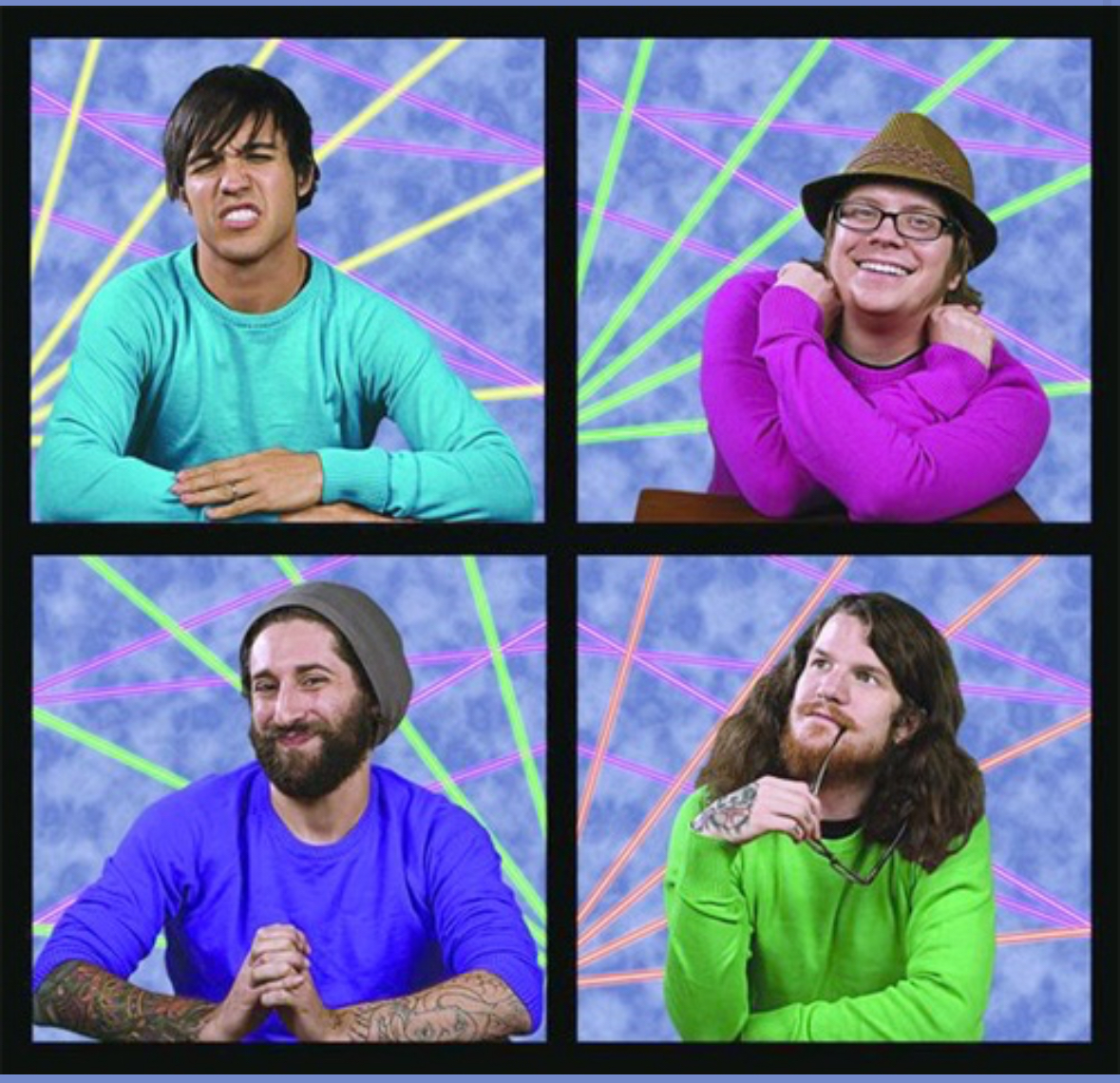 a group of four men in a band posing for a photo,  they are all smiling and each of them is wearing a different colored shirt.  the photo is in front of a laser light backdrop.