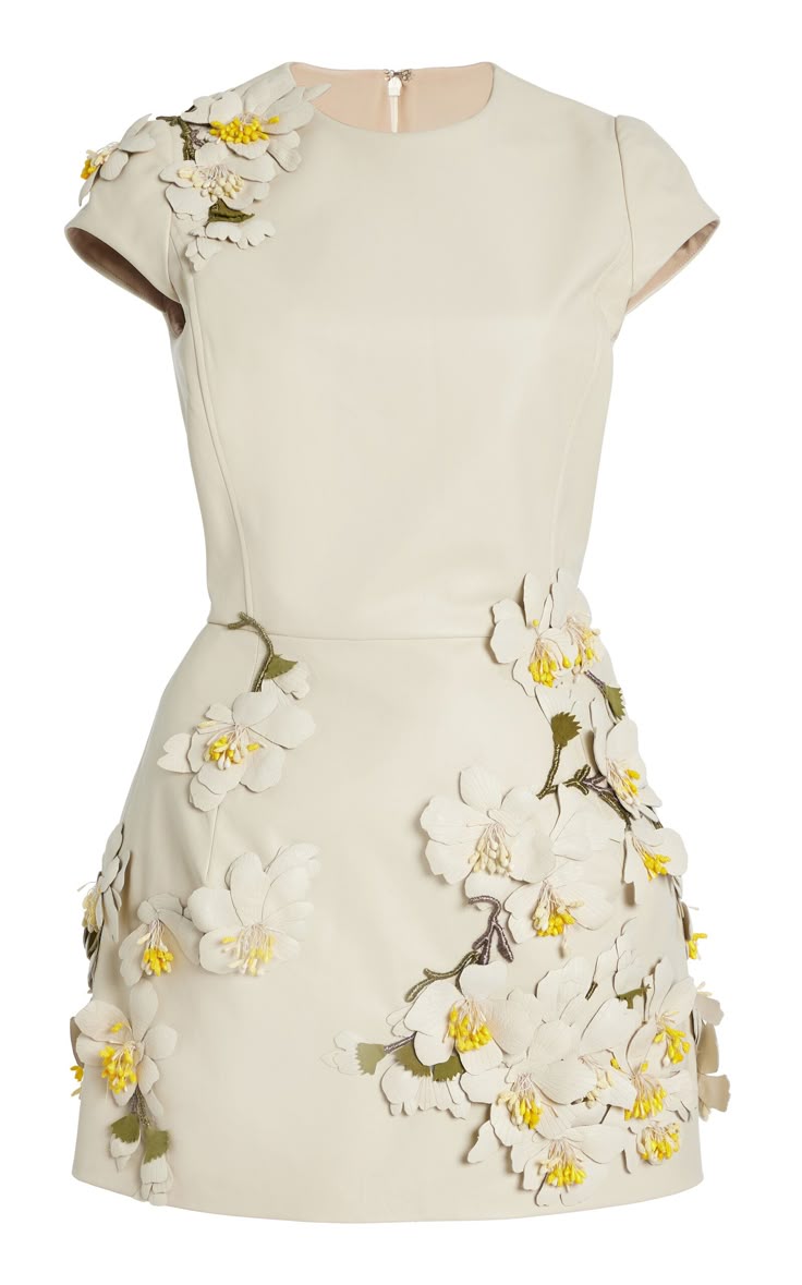 a closeup studio shot of a shortsleeved, creamcolored dress. the dress features floral appliques in white and yellow, cascading down the dress. the dress has a fitted bodice and a flared skirt. the background is white.