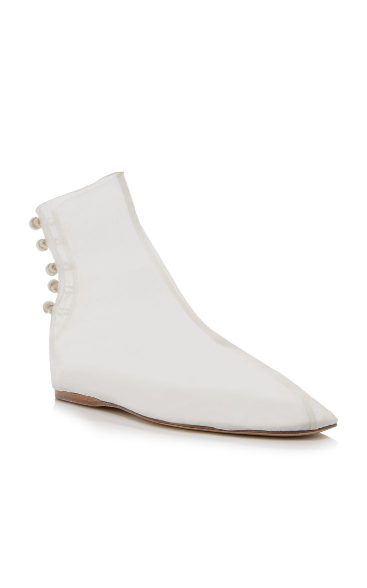 the image showcases a pair of women's white ankle boots. the boots are transparent or translucent, allowing the inside to be partially visible.  they have a pointed toe and a flat sole.  a line of small pearllike embellishments is visible on the back of the boots. the boots are presented on a white background, emphasizing their delicate and minimalist design. the overall style suggests a modern, possibly bridal or special occasion aesthetic.