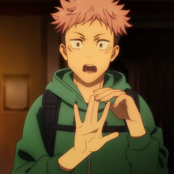 a young man with spiky pink hair and brown eyes is shown wearing a green hoodie and carrying a black backpack. he has an astonished expression on his face, with his mouth open and his hands raised in a gesture of surprise. the lighting is dim, suggesting an indoor setting, and the background features a wooden door and a partially obscured picture frame. overall, the image evokes a sense of shock and intrigue.