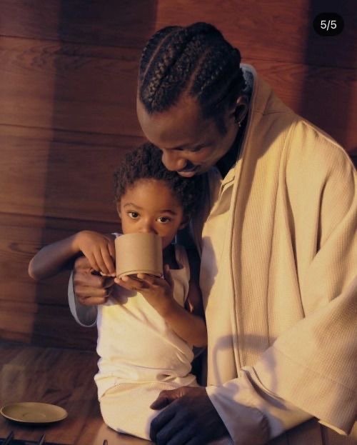 a father and daughter are sitting together, sharing a mug of something warm. the father is holding the daughter in his arms, and they are both smiling. the photo is warm and cozy, and it captures the love and affection between a father and daughter.