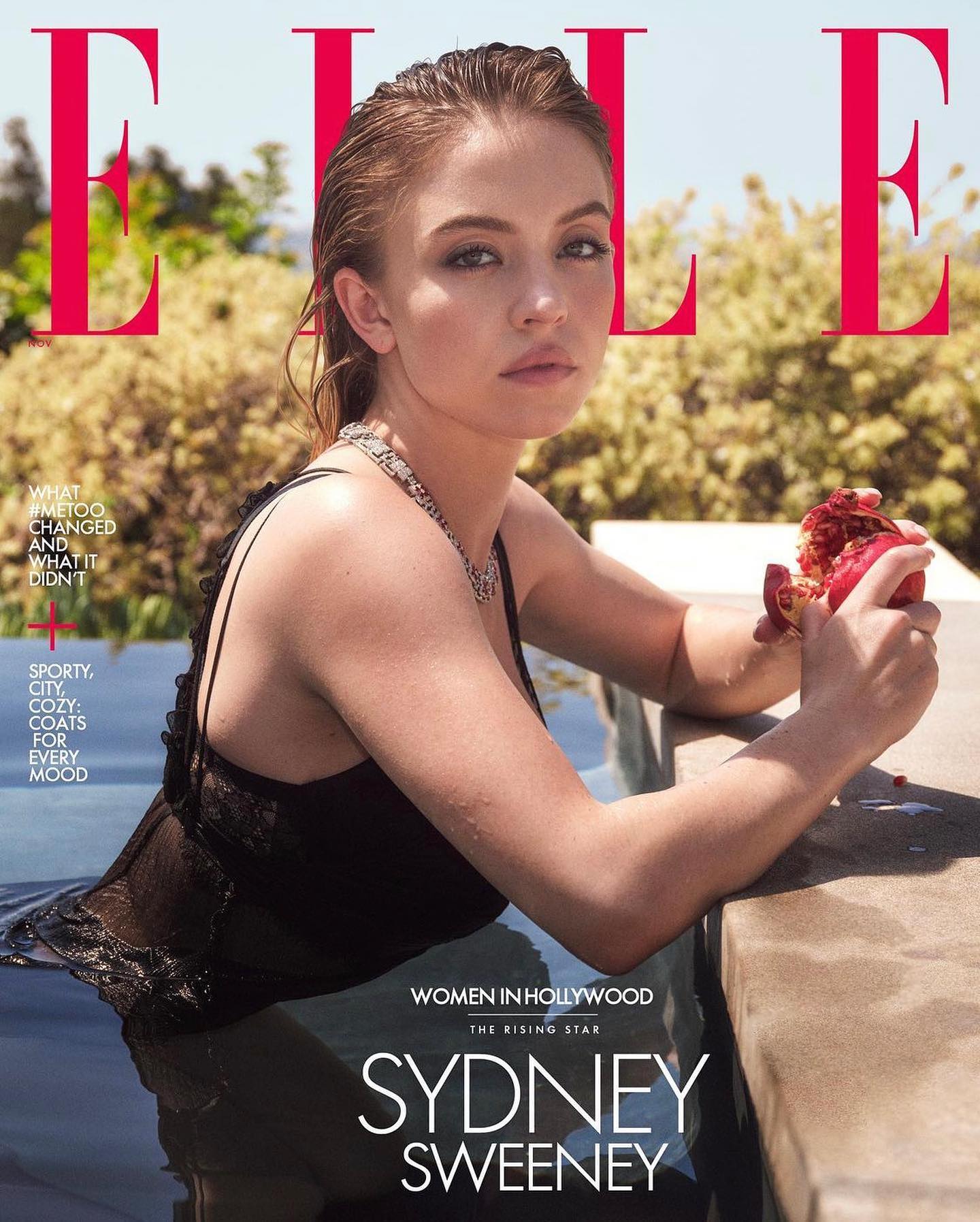 the image is a cover of elle magazine featuring actress sydney sweeney.  she's pictured partially submerged in a pool, wearing a black lace dress. her hair is wet and styled back from her face. she's holding a pomegranate, and the background shows a sunny, outdoor setting with lush greenery. the magazine's title "elle" is prominently displayed, along with text about "women in hollywood" and articles teased on the cover. the overall feel is glamorous and summery.