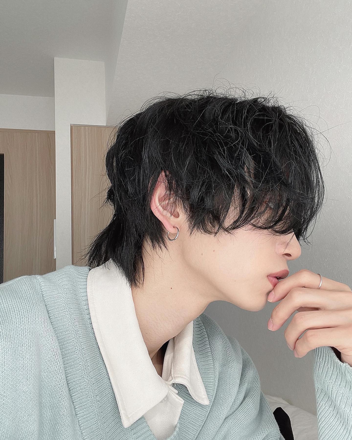 closeup selfie of a young asian man with black hair wearing a light blue sweater and a white undershirt. he's posing with his hand on his chin and has his face slightly turned to the side.