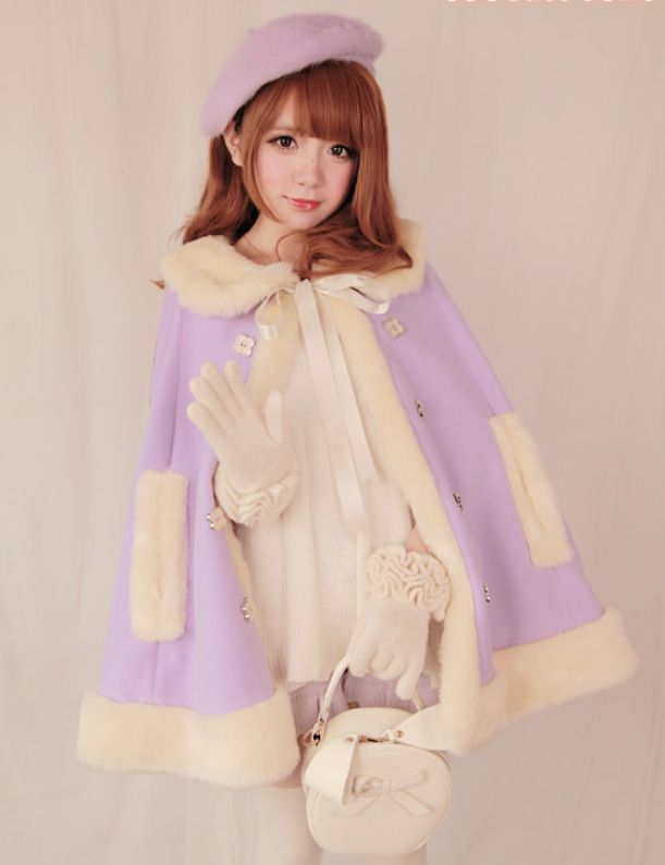 a young woman poses in a pastel purple winter cape with white faux fur trim. she is also wearing a purple beret, white gloves with flower embellishments, and carrying a round white purse with a bow. her overall look is very sweet and feminine, aligning with the lolita fashion aesthetic.