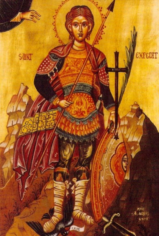 the image is an icon depicting saint expedite. he is shown standing, holding a spear in his right hand and a shield in his left. he wears roman armor and a halo is over his head. a cross with the word "hodie" is on the left side of the image. there is a palm branch behind the cross. at his feet, a crow is depicted. the words "saint expedite" are written above him. a hand is present on the left side of the top, with the fingers gesturing downward.