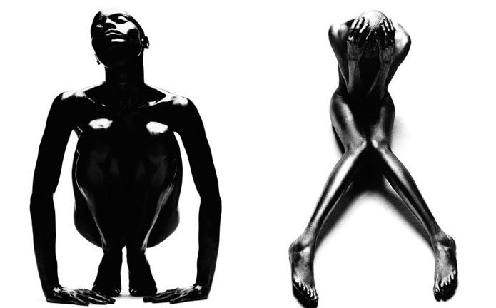 the image is a diptych, showcasing two black and white photographs of nude female figures.  both women have dark skin and appear to be coated in a substance that gives their bodies a smooth, almost sculpted appearance. the left image depicts a woman in a crouched position, her head tilted back, suggesting a feeling of openness or vulnerability.  the right image shows a woman sitting with her legs crossed and her hands covering her face, conveying a more introspective or guarded mood.  the stark contrast between the figures and the white background highlights their form and creates a powerful visual impact. the style is highly stylized and reminiscent of fine art photography.