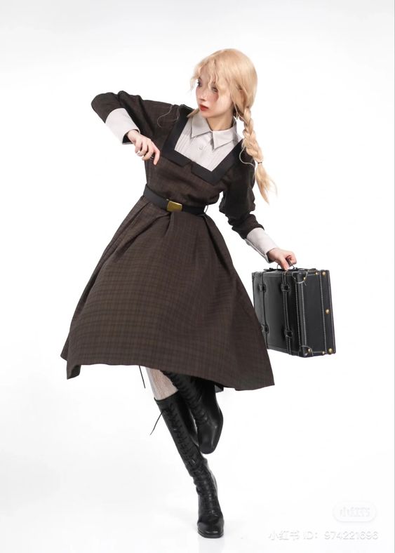 a blonde woman wearing a vintagestyle brown plaid dress with a white blouse and a black belt poses in a studio setting. she is holding a black briefcase and has one leg extended forward. the background is white, and the lighting is bright.