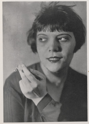 a black and white closeup portrait photograph of a young woman from the 1920s. she has a bobbed hairstyle and is holding a cigarette in her hand, looking off to the side with a somewhat pensive expression. the photo is in a style typical of studio portraits from the era, showing a clear focus on the woman's features and attire. the image has a somewhat soft and slightly grainy quality consistent with vintage photography.
