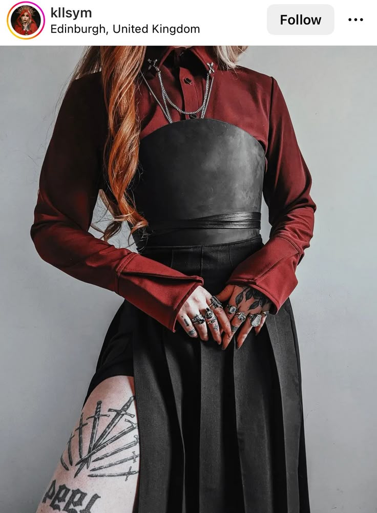 a woman is wearing a fashionable outfit consisting of a red collared shirt, a black corset, and a black pleated skirt with a slit. she has red hair and is wearing several rings on her fingers. she also has tattoos on her hands and leg. she is located in edinburgh, united kingdom and is a person named kllsym.