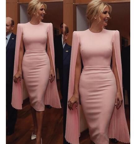 the image shows two identical pictures of ivanka trump wearing a pale pink midi dress with pleated cape sleeves. the dress is formfitting and kneelength. she is standing in a hallway or formal setting, with other people in the background who are out of focus. the overall impression is one of elegance and sophistication.