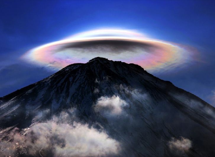 a stunning panoramic view of a majestic mountain, possibly a volcano, rising majestically from a sea of clouds. the sky above is ablaze with vibrant colors, creating a breathtaking display of natural beauty. an iridescent ring or halo surrounds the mountain, adding an ethereal and mystical quality to the scene. the clouds below the mountain, resembling wispy cotton, create a sense of depth and dimension, while the summit of the mountain pierces through the clouds, symbolizing a sense of achievement and aspiration. the overall atmosphere is serene and peaceful, inspiring awe and wonder in the viewer.