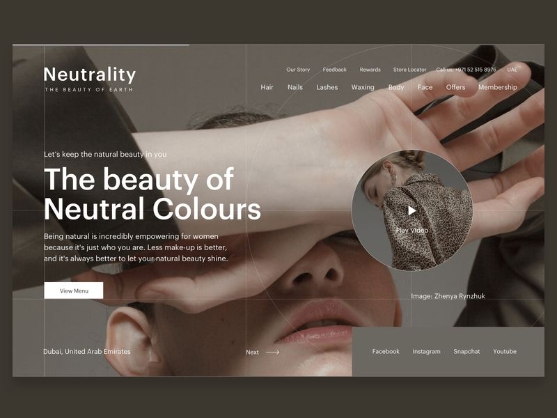 the image is a minimalist website design for a beauty salon or spa. the website is promoting the idea of natural beauty and the power of neutral colors in makeup and skincare. the main image features a woman's face and hand, highlighting her natural beauty. the background of the image is a simple grid pattern, which creates a modern and elegant look. the website also includes a menu bar with links to different pages, as well as social media icons. the overall message of the website is that beauty comes from within and that embracing your natural features is the best way to feel confident and beautiful.