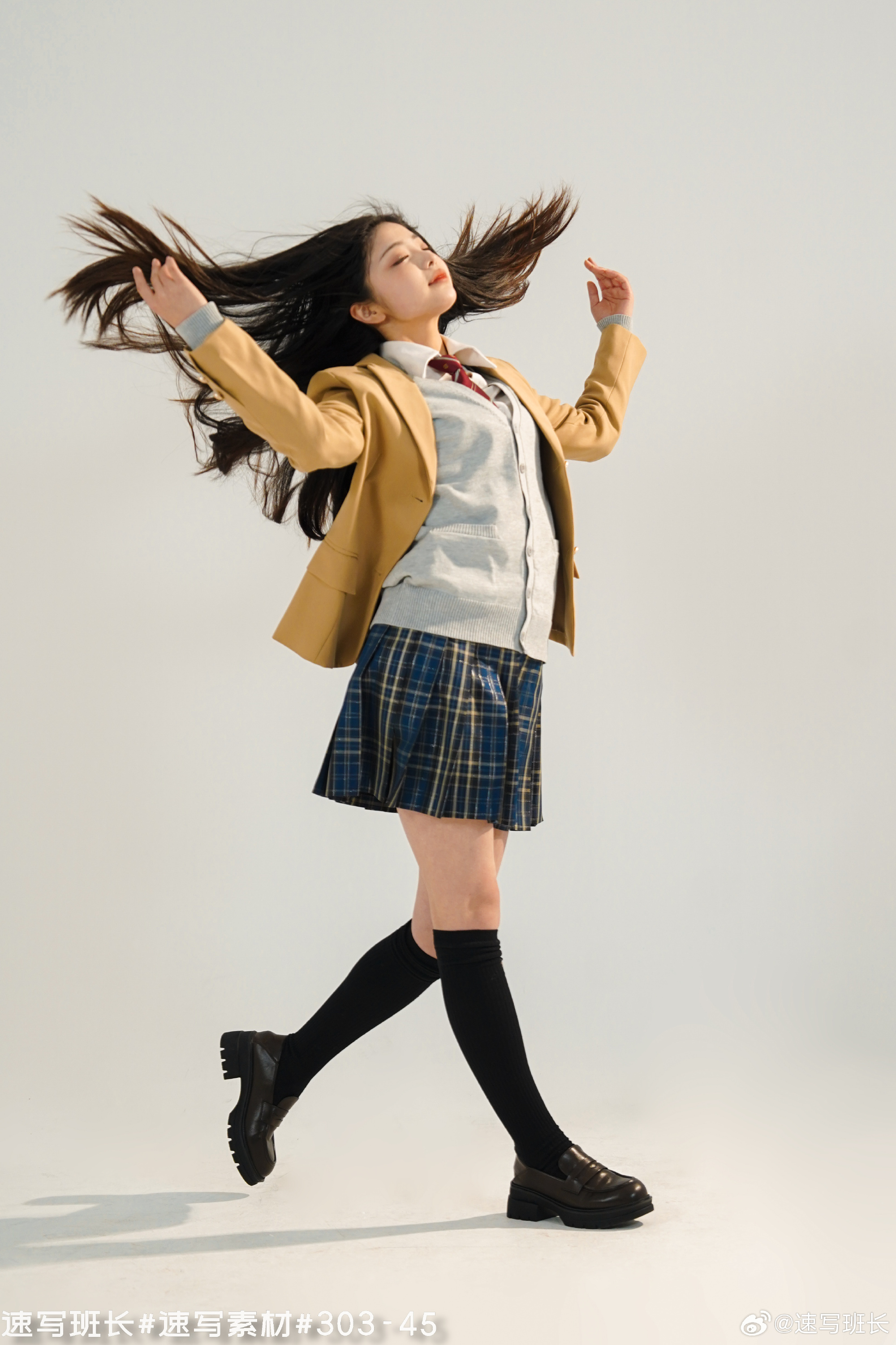 a young asian woman in a japanese school uniform, stands on a white background in a studio. she is wearing a yellow blazer, grey sweater vest, a blue and green plaid skirt, black knee high socks, and black platform loafers. her long, black hair is being tossed around her head as she is in midstride. the image is brightly lit with studio lighting.