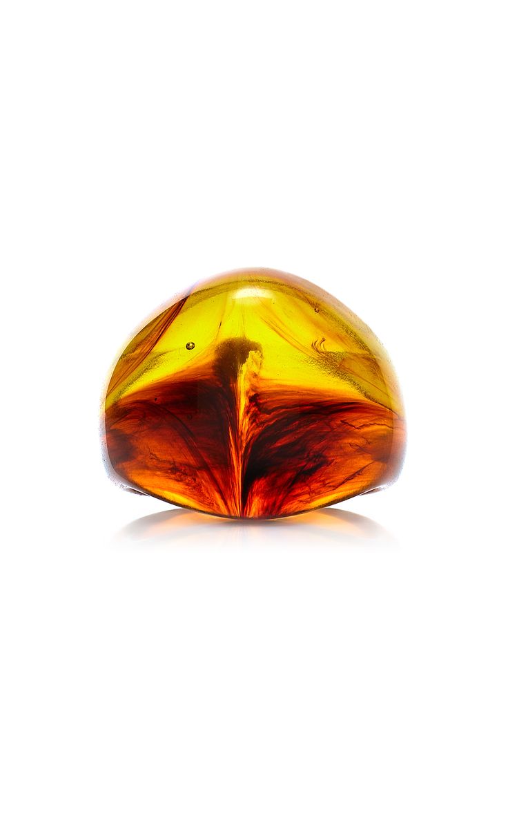 a closeup shot of a polished amber stone. the amber is oval shaped and has a yellow, red, and brown color. the stone is sitting on a white background and the background is reflected in the stone.