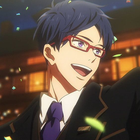 the image shows a young anime man with blue hair and purple glasses smiling brightly. he is wearing a black suit with a white shirt and purple tie. he seems to be indoors with confetti falling around him, suggesting a celebratory atmosphere. the lighting is warm and highlights his facial features, especially his smile.