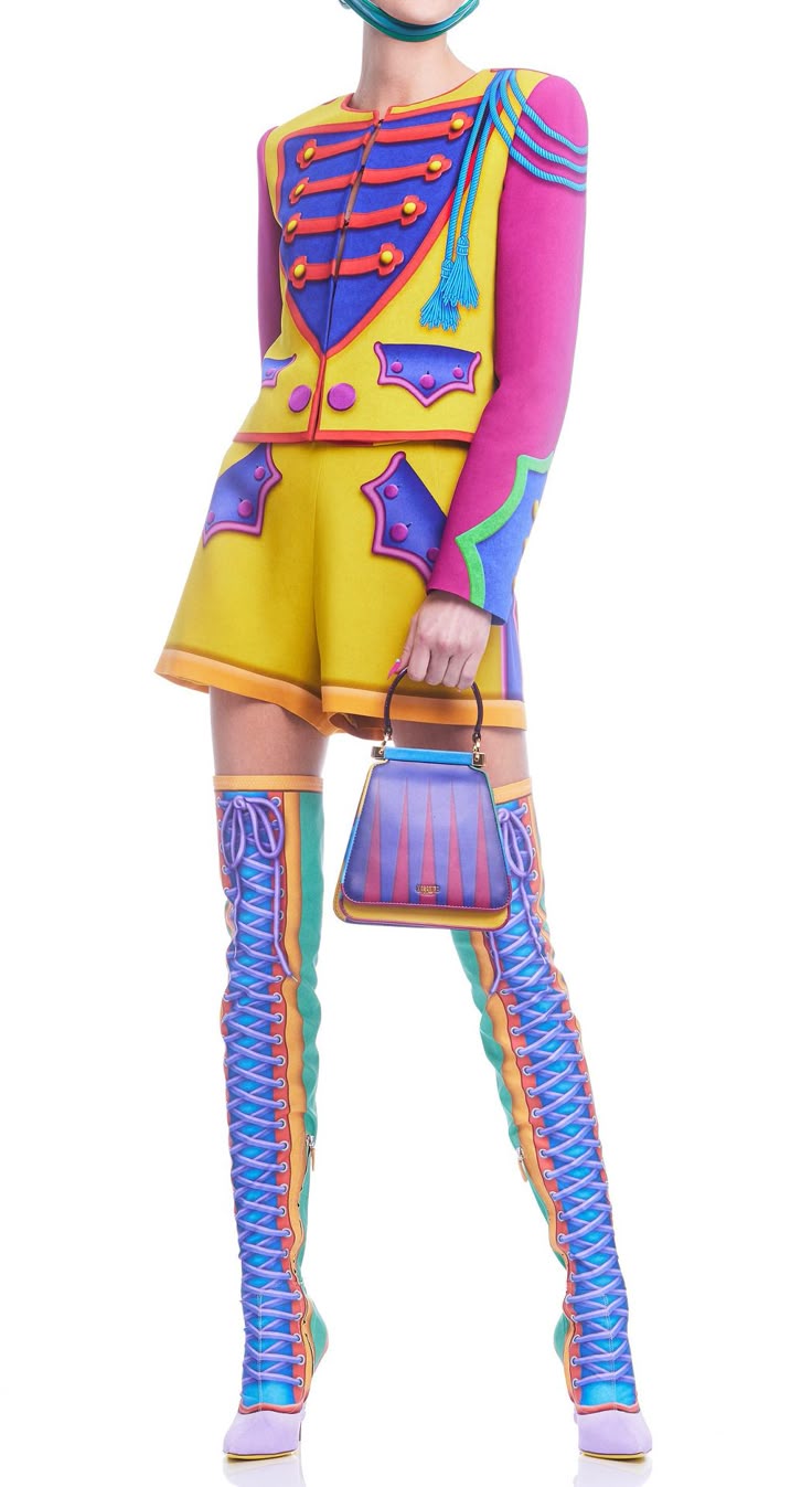 a fullbody shot of a woman wearing a bright, colourful outfit consisting of a jacket, shorts, and kneehigh boots, holding a handbag, against a white background. the jacket is yellow with blue and red detailing, with a pink sleeve, designed in a military style. the shorts are yellow with matching blue and red detailing. the boots are kneehigh and multicoloured, with green, blue, and orange stripes. the handbag is striped in purple, blue, and yellow. the woman is standing with a slight pose, and the entire image is welllit and focused.