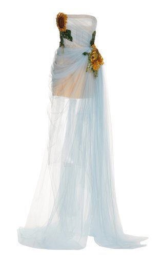 a strapless evening gown in a light blue tulle fabric. the dress has a short base layer and a long, flowing overlay. sunflower embellishments are featured on the bodice of the dress.
