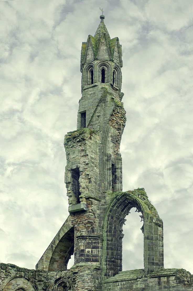 the image shows the ruins of st andrews cathedral, an old stone structure with a tower and arches, set against a cloudy sky.