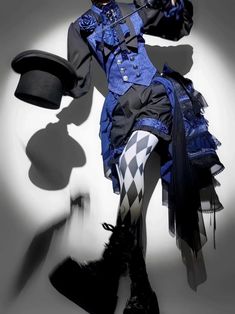 a person is standing in a dynamic pose wearing an elaborate blue and black lolita fashion outfit.  the outfit features a tailcoat with intricate detailing, a ruffled blouse, bloomers, and thighhigh socks with a harlequin pattern. they are also wearing a top hat and holding a cane.  the image is shot against a white background with dramatic lighting.
