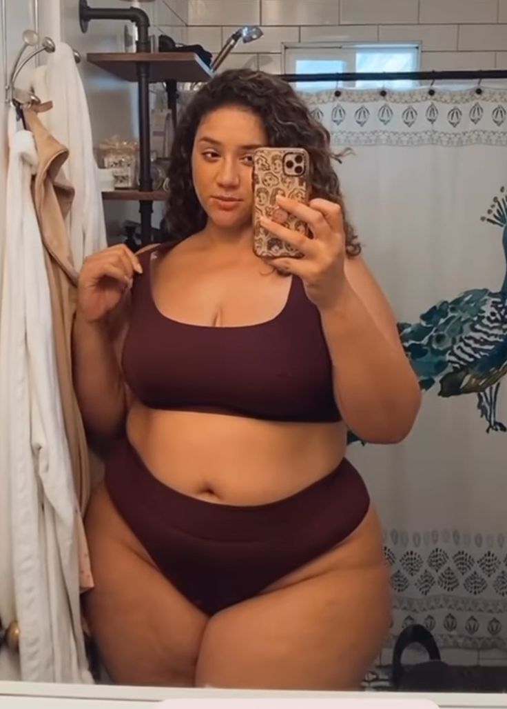 a woman in brown underwear taking a mirror selfie in a bathroom.