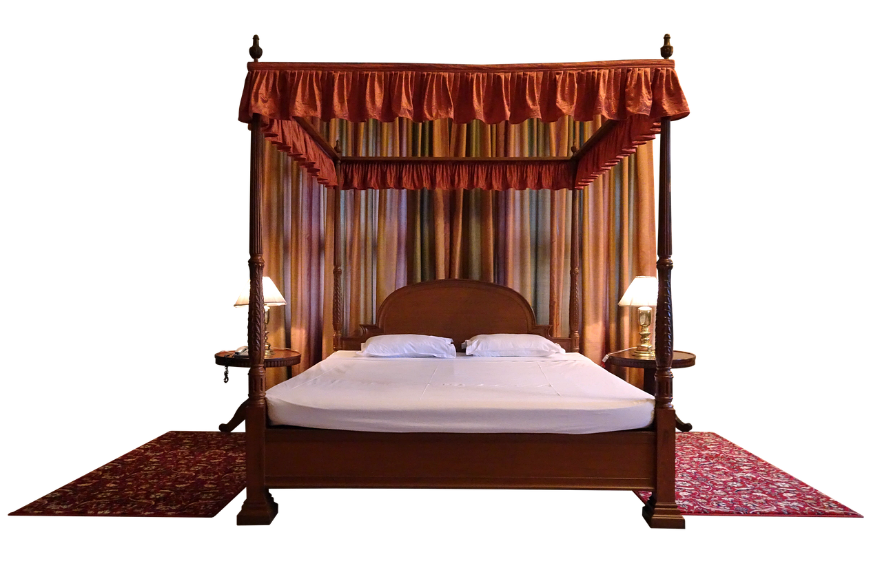 this image shows a fourposter bed in a bedroom setting. the bed has a wooden frame with a canopy draped in orange fabric. two white pillows rest on a white sheet. two lamps are placed on bedside tables on either side of the bed. a patterned carpet is laid out in front of the bed, and curtains hang behind the bed, creating a backdrop. the background is black.
