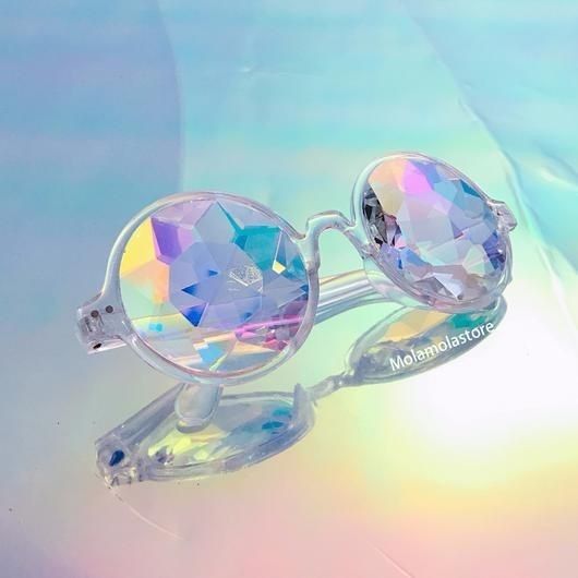 the image shows a pair of kaleidoscope glasses with clear frames and prism lenses, creating a rainbow reflection effect. the glasses are positioned on a holographic background, and the refracted light through the lenses produces an abstract, iridescent, and surreal visual. a watermark "molamolastore" is visible on the reflective surface.
