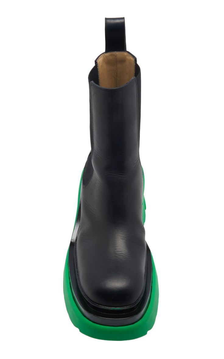 the image shows a pair of women's black leather ankle boots with a chunky green sole. the boots are a chelsea style, with elasticated sides. they are shown from a fronton perspective, and are set against a white background. the boots appear to be made of highquality leather and have a modern, stylish design.