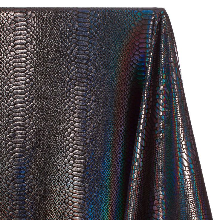 the image shows a closeup of a fabric with a snakeskin pattern. the fabric has a holographic, iridescent finish that creates a shiny, colorful effect. the snakeskin pattern is detailed and realistic, resembling reptile skin. the texture of the fabric appears smooth and possibly synthetic.