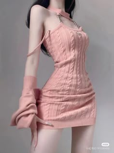 a woman in a pink sweater dress poses in a studio. she is looking at the camera and her hair is long and flowing.