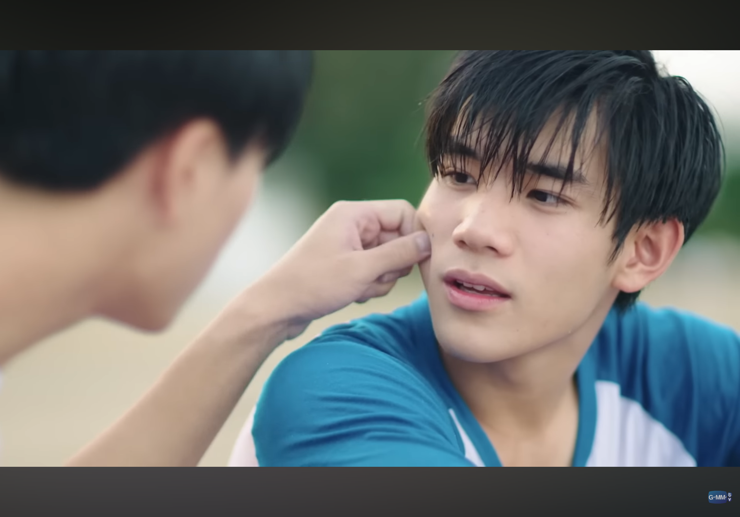 the image captures a closeup moment between two young men. the man on the left gently touches the cheek of the man on the right. the lighting is soft and natural, creating a warm and intimate atmosphere. the focus on their faces and the close proximity suggest a deep connection and affection between them.
