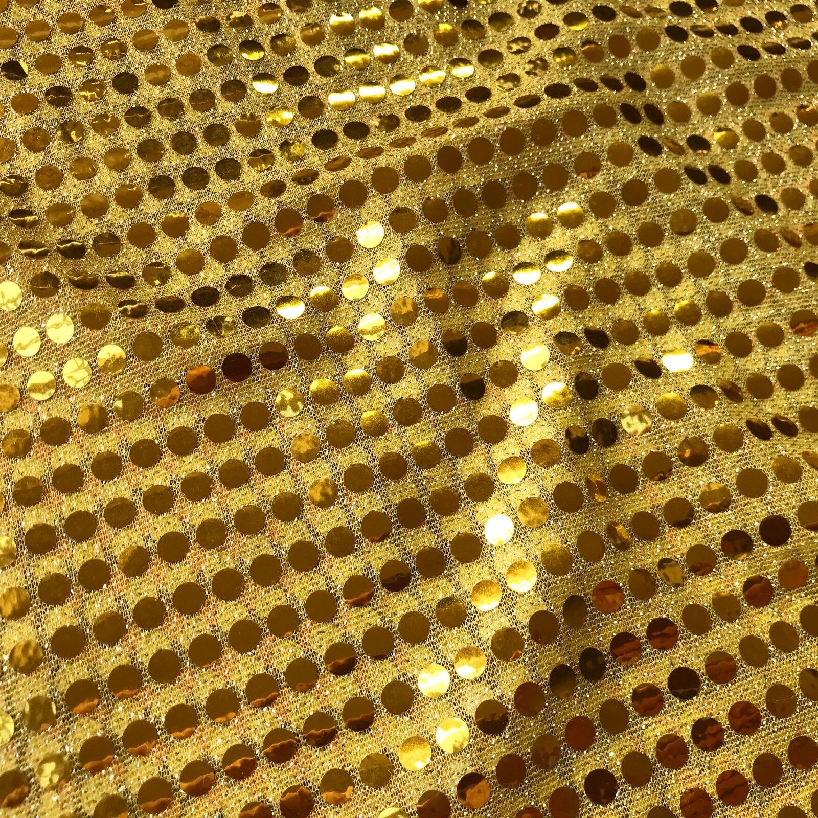 a closeup image of gold sequined fabric, showcasing its shiny and textured surface.