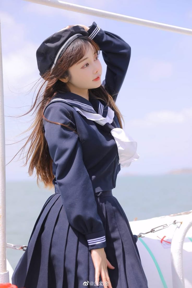 a woman is standing outdoors in a sailor uniform and a beret. she is looking away from the camera.