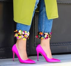a woman is wearing a green jacket and jeans with sequin detailing at the hems. she is also wearing pink high heels.