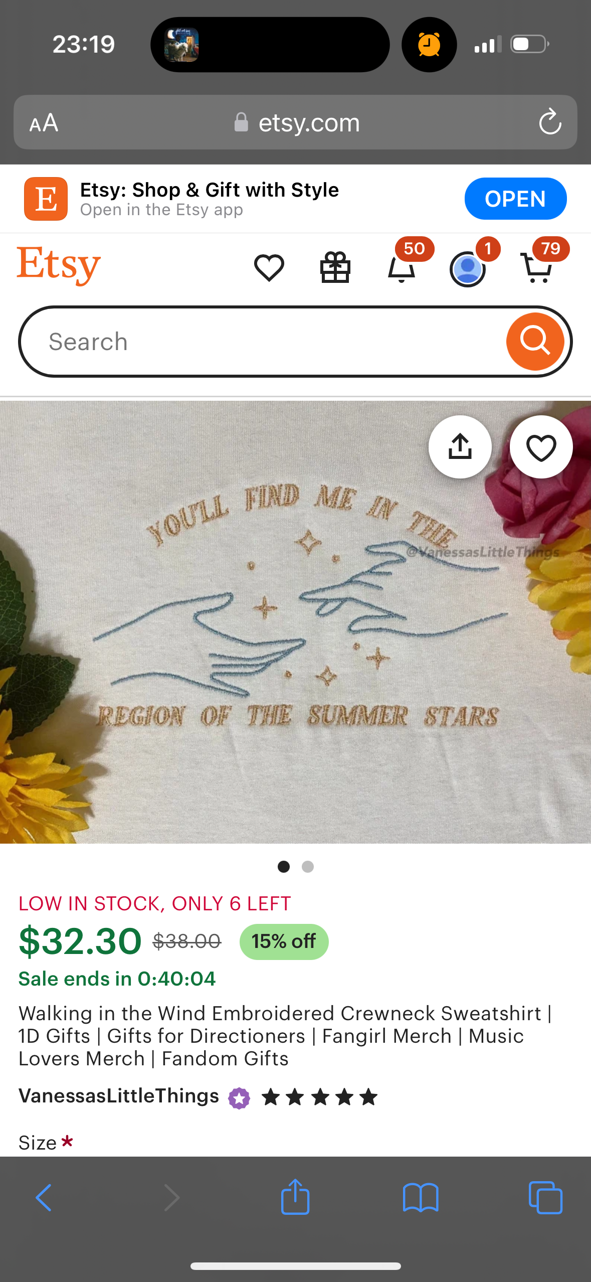 the image is a screenshot of an etsy listing for a white embroidered crewneck sweatshirt that reads "you'll find me in the region of the summer stars." the sweatshirt is for sale on the etsy shop "vanessaslittlethings."  the listing includes details about the product such as the price, availability, and a 15% discount. it also includes keywords such as "1d gifts", "directioners", "fangirl merch", "music lovers merch", and "fandom gifts". the image is taken on a smartphone device and includes a white background, grey and black navigation icons at the bottom of the image, a few yellow, red and green flowers on the right side of the image, and a screenshot of the top of the etsy app with a search bar and the text "etsy: shop & gift with style."