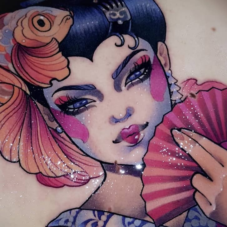 closeup photograph of a colorful, stylized tattoo of a japanese geisha holding a fan. the geisha has blue hair, bright makeup, and a large koi fish tattoo on her shoulder.  the tattoo has a soft, dreamlike quality.