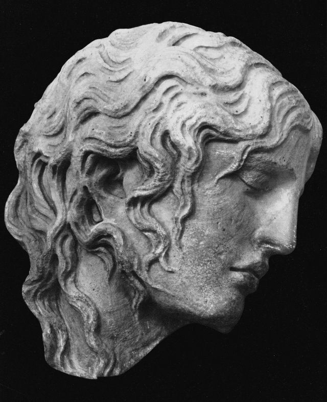 a black and white image shows a profile view of a stone sculpture of a head and bust. the sculpture has wavy hair, closed eyes, and a serene expression. the style appears to be classical or ancient greek.