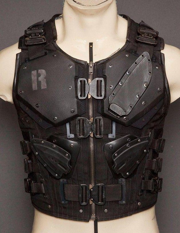 a black tactical vest with numerous straps and buckles, adorned with a knife sheath. the vest appears to be made of durable,  reinforced material,  likely intended for  protection and  tactical purposes. the vest's construction suggests a high level of functionality and resilience, emphasizing its role in  combat or  security operations.  the  inclusion of a  knife sheath on the front of the vest further reinforces its  tactical  nature.