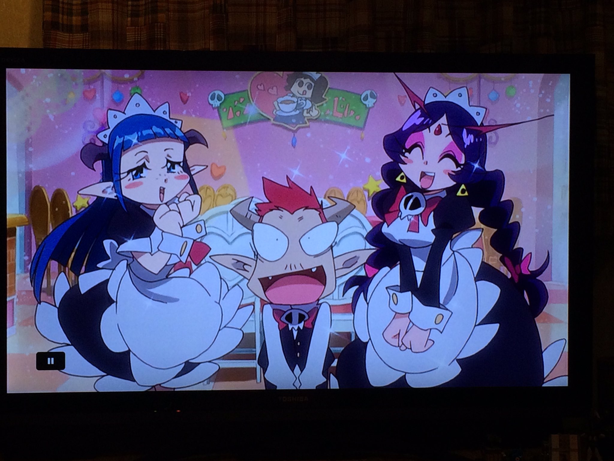 the image shows a scene from an anime cartoon featuring three characters dressed in maid outfits. two female characters, one with blue hair and the other with purple hair, flank a surprisedlooking male character with red hair. they are in a brightly lit pink room with heartshaped decorations. the characters' exaggerated expressions and the vibrant colors contribute to the playful and humorous tone of the image.