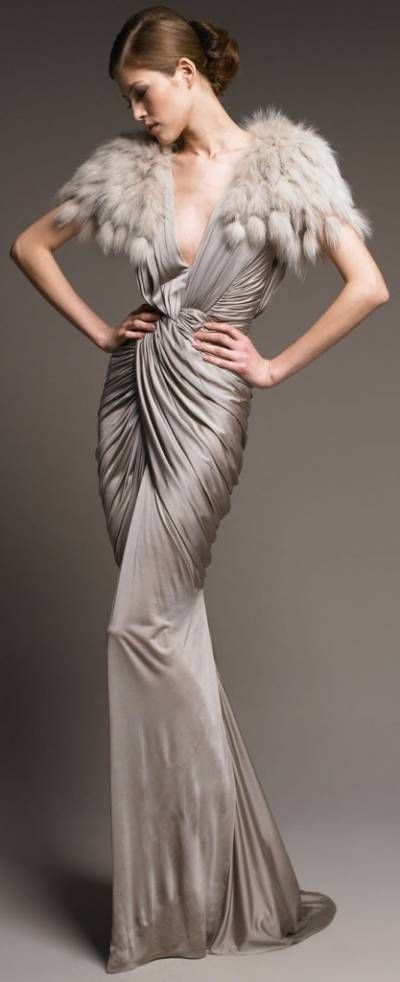 a woman in a glamorous, draped gown, with a fur stole draped over her shoulders, poses for the camera in a studio. she looks sophisticated and elegant. the image is a beautiful example of fashion photography.