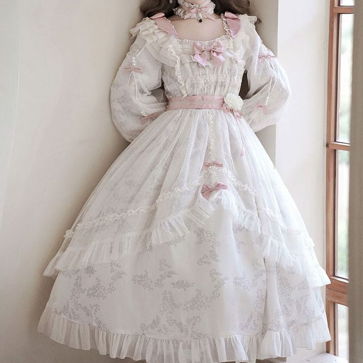 a young woman stands indoors, bathed in soft, natural light, modeling an elegant white lolita fashion dress. the dress is characterized by its intricate lace detailing, delicate floral patterns, and a full, flowing skirt.  the romantic design features puffed sleeves, a sweetheart neckline, and a pink ribbon accentuating the waist.  the overall effect is one of vintageinspired elegance with a touch of kawaii charm.