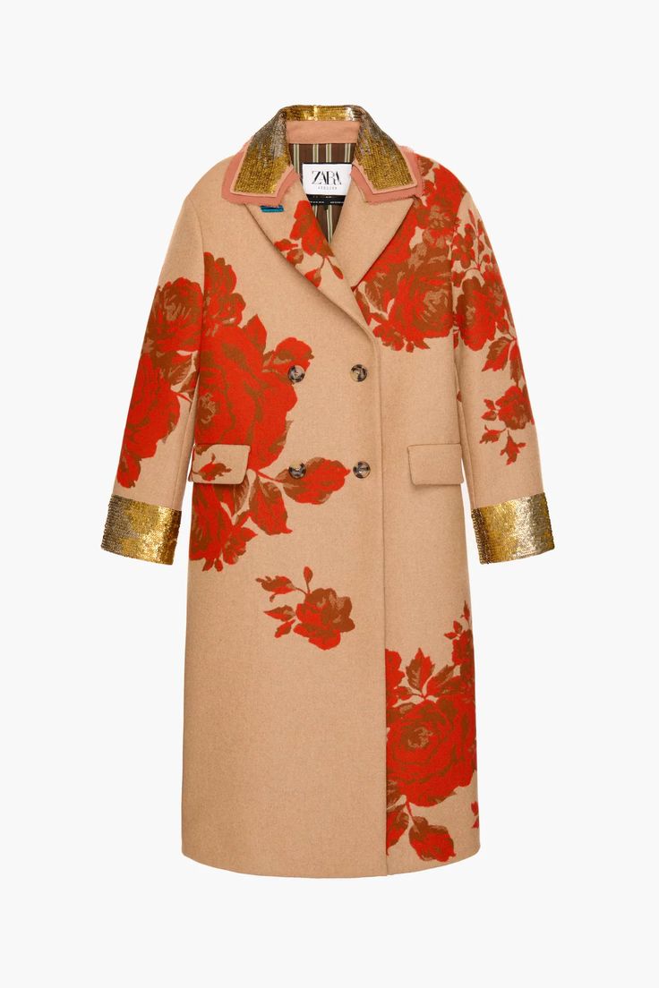 a zara beige, kneelength, doublebreasted coat with a red floral pattern. the coat has long sleeves with gold trim at the cuffs, a collar also trimmed with gold, and two pockets. the background is plain white.